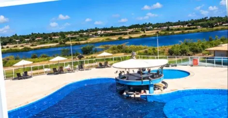 Piscina adulto do Villa das Águas com bar molhado ao centro e a lagoa ao fundo